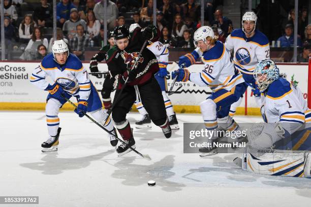 Troy Stecher of the Arizona Coyotes skates after a loose puck while being defended by JJ Peterka and Rasmus Dahlin of the Buffalo Sabres during the...