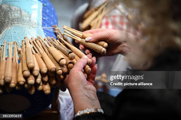 November 2023, Saxony, Annaberg-Buchholz: Daniela Böhme twirls the wooden bobbins in her hands. There is evidence that bobbin lace has been made in...