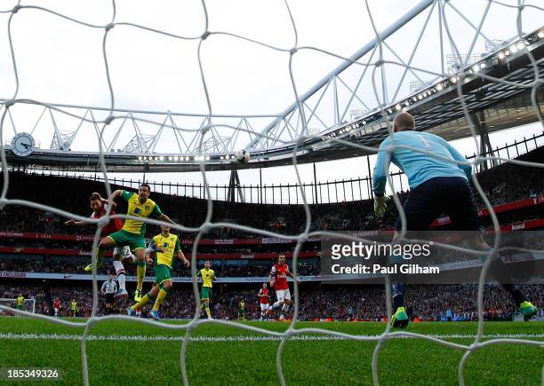 Mesut Oezil of Arsenal beats Russell Martin of Norwich City as he scores their second goal with a header past goalkeeper John Ruddy during the...
