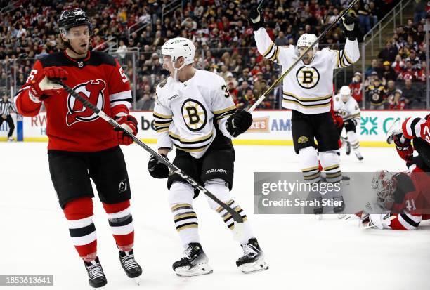 Morgan Geekie and James van Riemsdyk of the Boston Bruins react after a goal scored by Geekie as Vitek Vanecek and Erik Haula of the New Jersey...