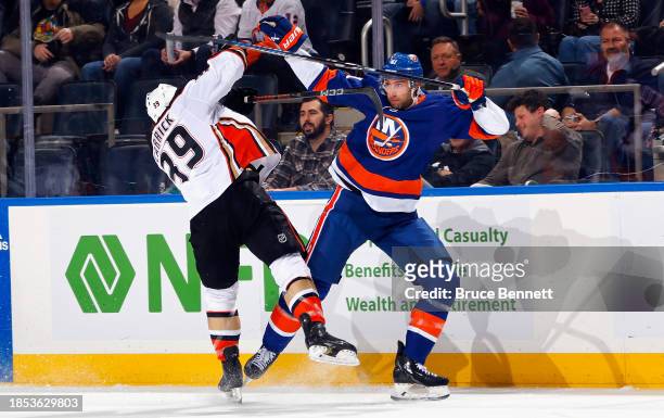 JSam Carrick of the Anaheim Ducks and Robert Bortuzzo of the New York Islanders collide during the first period at UBS Arena on December 13, 2023 in...