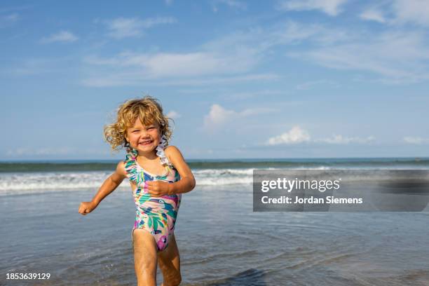 a young girl with a big smile running down the beach in costa rica. - playa tamarindo - fotografias e filmes do acervo