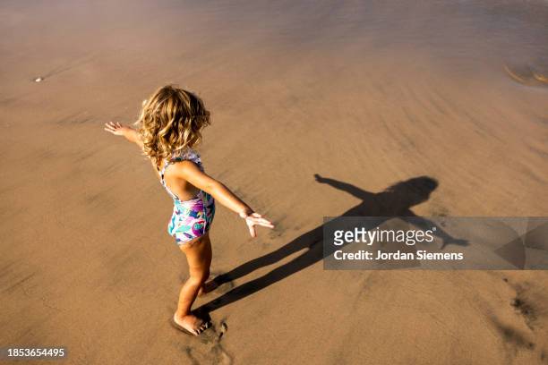 a young girl standing in the sand on a beach. - guanacaste beach stock pictures, royalty-free photos & images