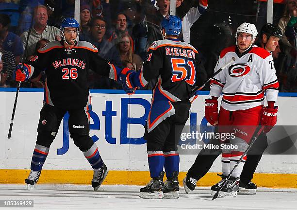 Matt Moulson of the New York Islanders celebrates his 2nd period goal with teammate Frans Nielsen as Justin Faulk of the Carolina Hurricanes looks on...