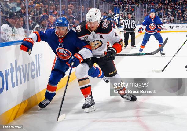 Cam Fowler of the Anaheim Ducks checks Kyle Palmieri of the New York Islanders during the second period at UBS Arena on December 13, 2023 in Elmont,...