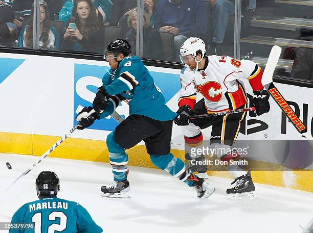 Joe Pavelski of the San Jose Sharks handles the puck against Dennis Wideman of the Calgary Flames during an NHL game on October 19, 2013 at SAP...