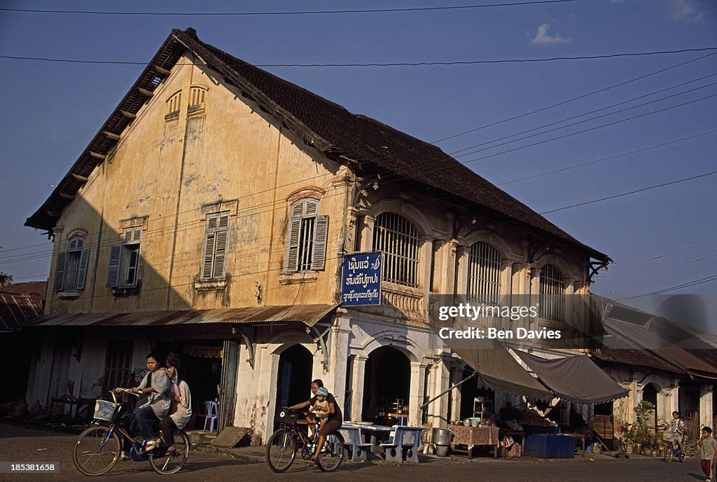 Locals ride bicycles in front of the imposing facade of a...