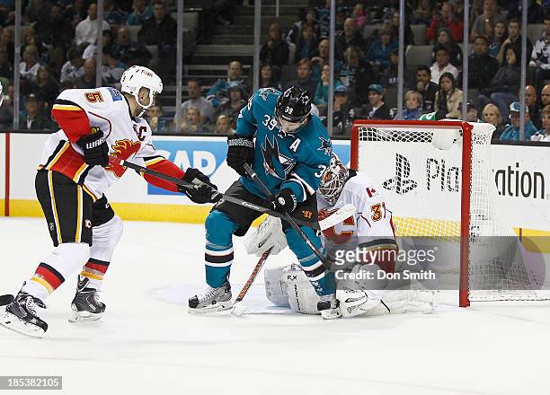 Logan Couture of the San Jose Sharks blocks the net against Mark Giordano and Karri Ramo of the Calgary Flames during an NHL game on October 19, 2013...
