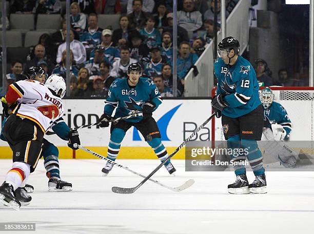 Justin Braun, Patrick Marleau and Antti Niemi of the San Jose Sharks defend the net against Dennis Wideman of the Calgary Flames during an NHL game...