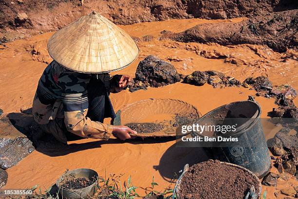Woman tin miner pans the muddy waters of the Pathene Basin outside the Phontiou Tin Mine in Khammouan Province in Central Laos in the hope of...