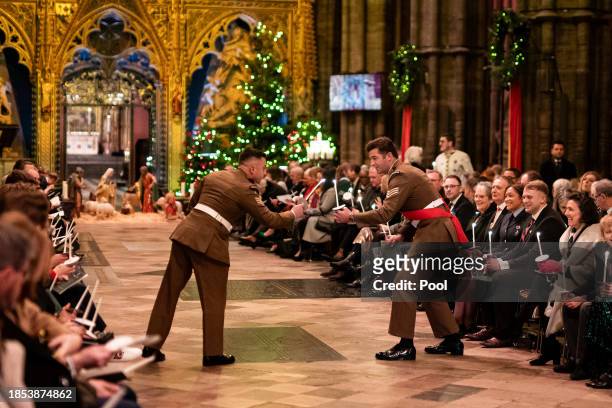 Two military personal light candles during the Royal Carols - Together At Christmas service at Westminster Abbey on December 8, 2023 in London,...