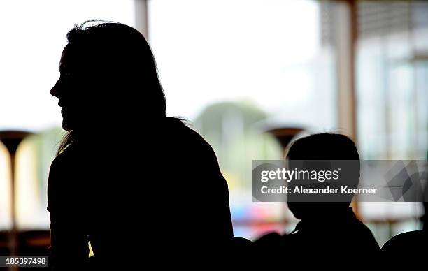 Bettina Wulff sits togehter with her son Linus prior a church service at the Expowal on October 20, 2013 in Hanover, Germany. The church service is...