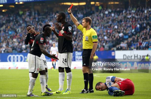 Referee Tobias Welz shows the red card to Antonio Ruediger of Stuttgart next to Rafael van der Vaart of Hamburg during the Bundesliga match between...