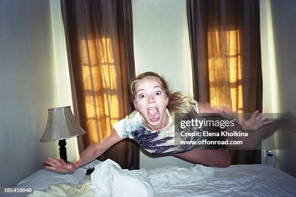 Girl flying above a bed in a room