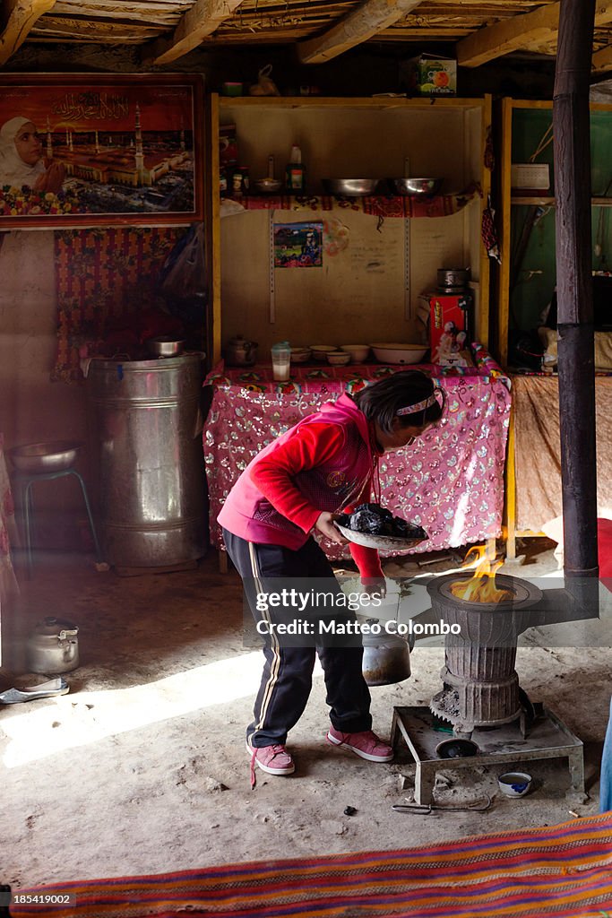 Kyrgyz girl putting coal in the stove in her yurt