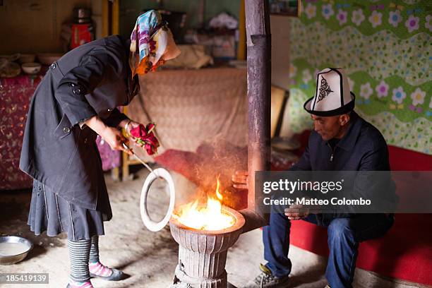 kyrgyz man and woman near the stove inside a yurt - kyrgyzstan people stock pictures, royalty-free photos & images