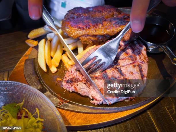 cutting into a beef steak and cajun chicken on a sizzling plate - eating cajun food stock pictures, royalty-free photos & images