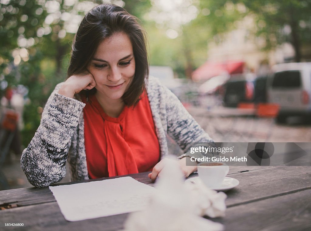 Woman writing a letter in cafe