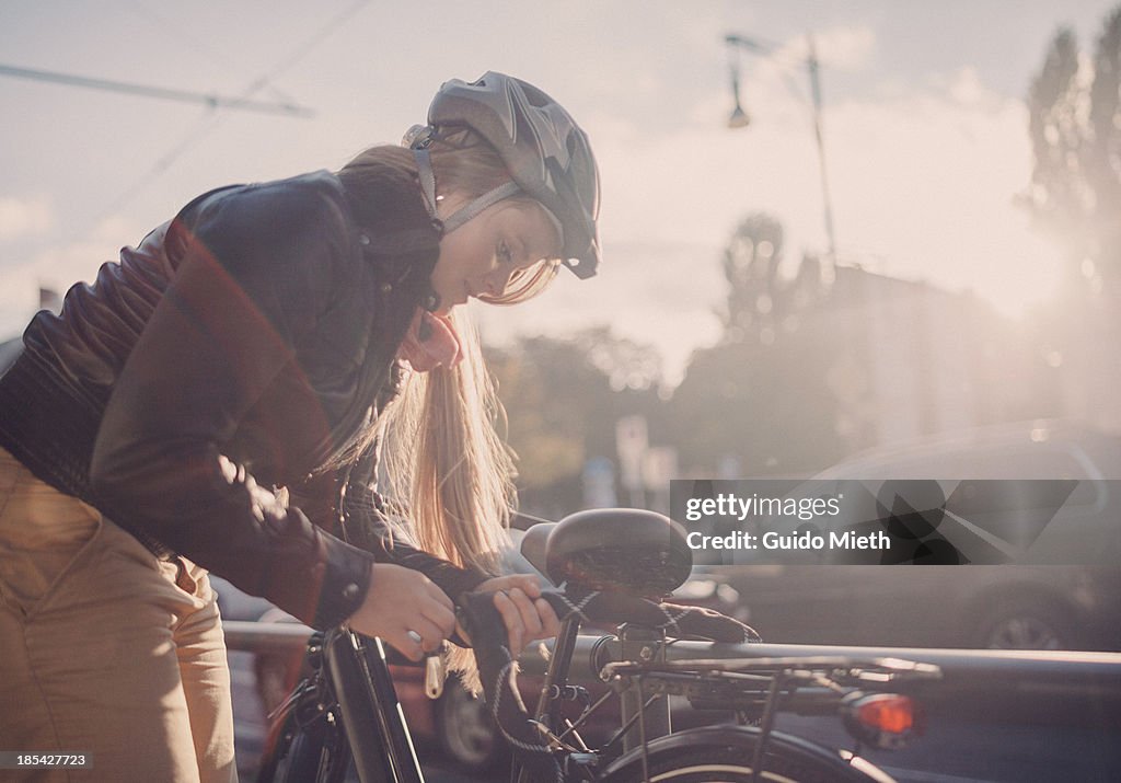 Woman locking her bike in city.