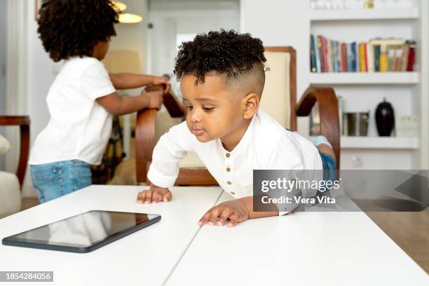 naughty african little boys playing with technology on living room - geschwister frech stock-fotos und bilder