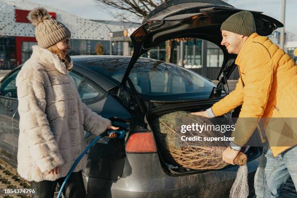 loading the christmas tree while the electric cars is being charged - fuel efficient stock pictures, royalty-free photos & images