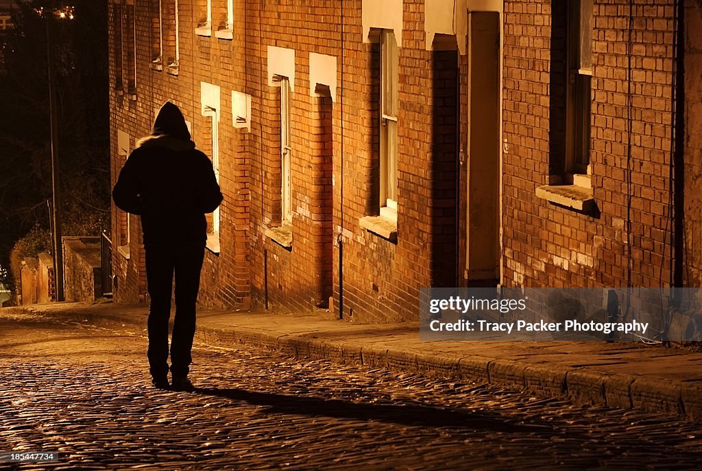 Silhouetted man stands outside a terrace at night.