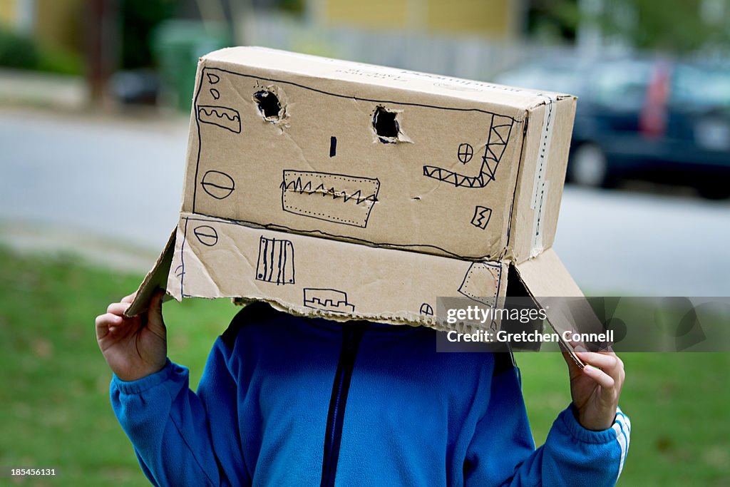 Boy wearing handmade mask made from cardboard box