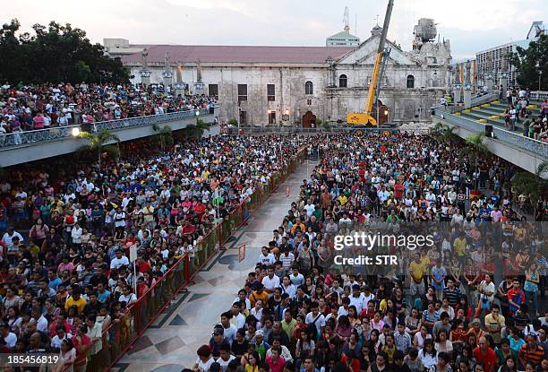 This photo taken on October 18, 2013 shows hundreds of devotees attending mass outside the Sto. Niño basilica, whose bell tower was destroyed during...