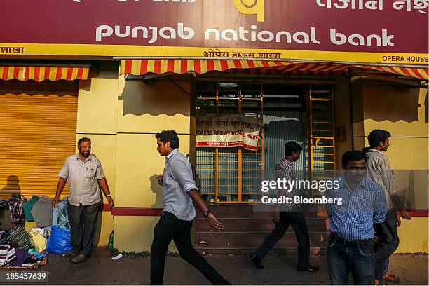 Pedestrians walk past a branch of Punjab National Bank in Mumbai, India, on Saturday, Oct. 19, 2013. Volatility in Indias rupee fell to a two-month...
