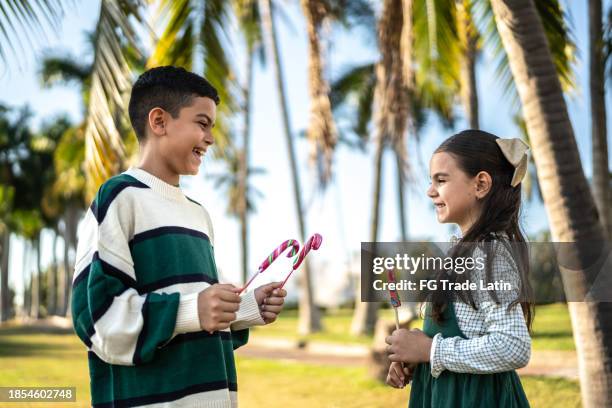 siblings having fun with christmas sweet in public park - 6 11 months stock pictures, royalty-free photos & images