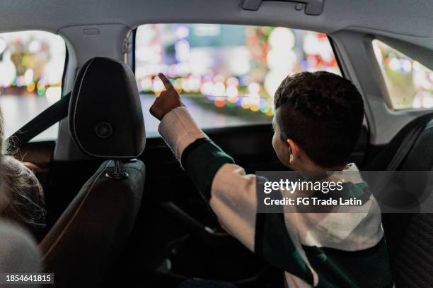 child boy looking for christmas lights through the car window - christmas lights stock pictures, royalty-free photos & images