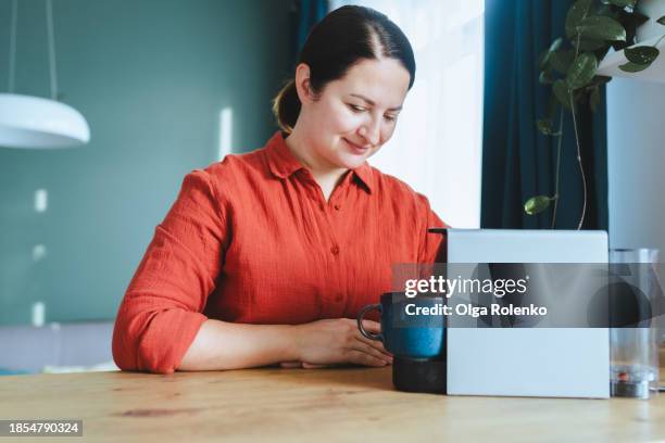 woman using capsule coffee machine in kitchen - single serve coffee maker stock pictures, royalty-free photos & images