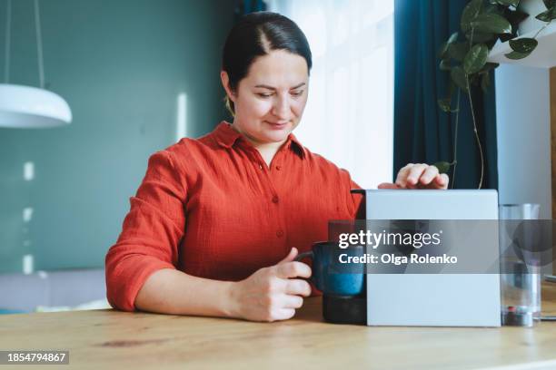 woman using capsule coffee machine in kitchen - single serve coffee maker stock pictures, royalty-free photos & images