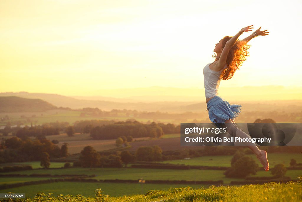 Girl Flying into air over countryside