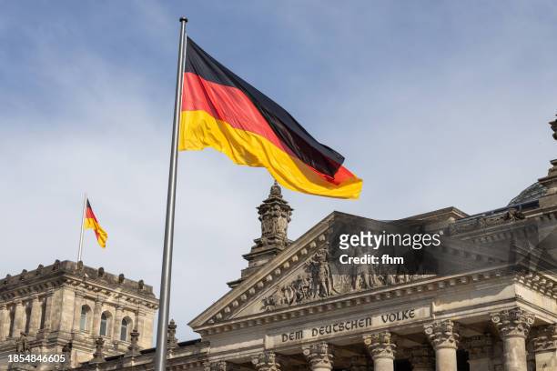 deutscher bundestag - reichstag building with german flags (german parliament building) - berlin, germany - german flag wallpaper stock-fotos und bilder