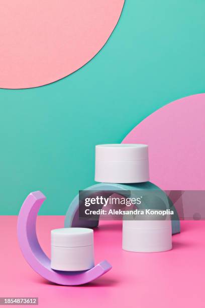 colorful 3d stage with set of three white cosmetics jars on pastel pink table with abstract geometric figures on turquoise mint green background. - mint green stock pictures, royalty-free photos & images