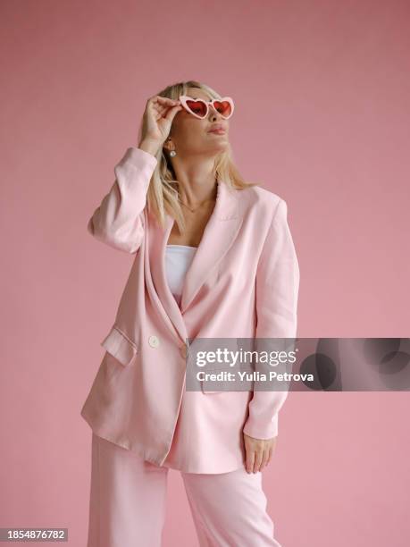 beauty shot of beautiful woman in monochromatic pink wearing heart-shaped glasses - 40 year old models stock pictures, royalty-free photos & images