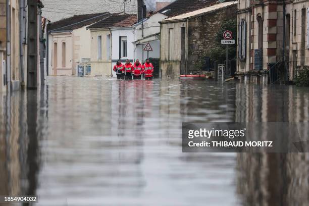 Firefighters walk through the water as the Charente river floods the town of Saintes, southwestern France, on December 17, 2023.