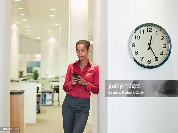 businesswoman in office using pda near a clock - clock person desk stockfoto's en -beelden