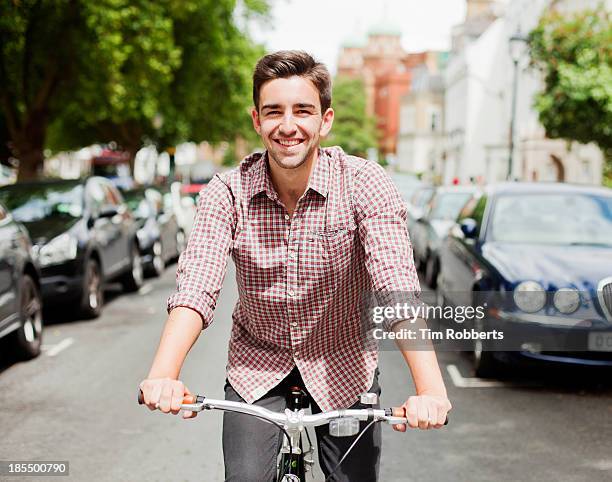 man cycling down a street. - green shirt stock pictures, royalty-free photos & images