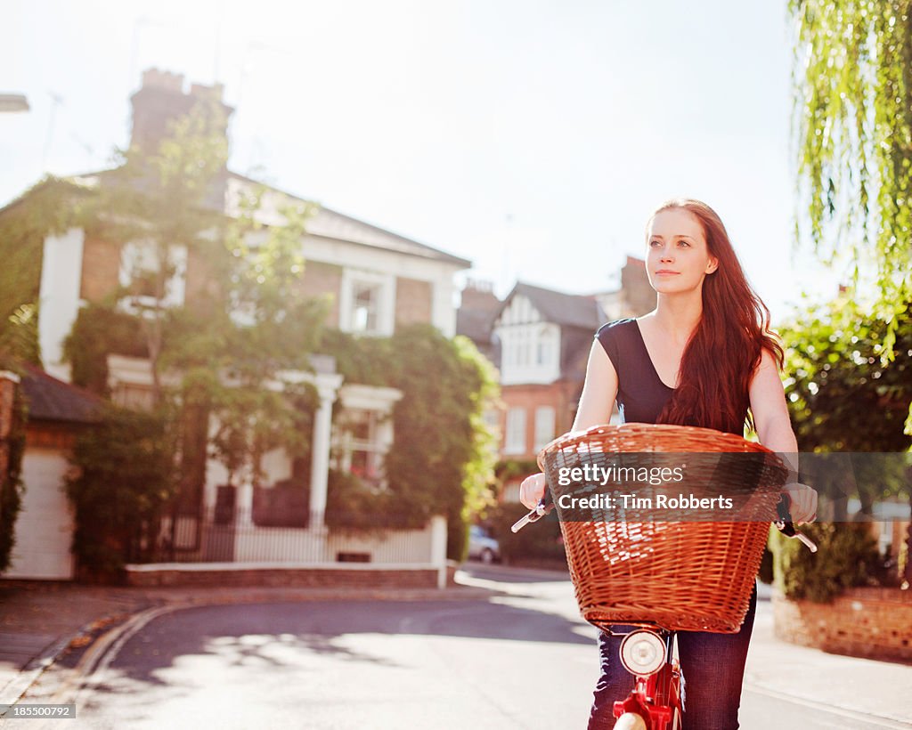 Woman cycling on streets on sunny day