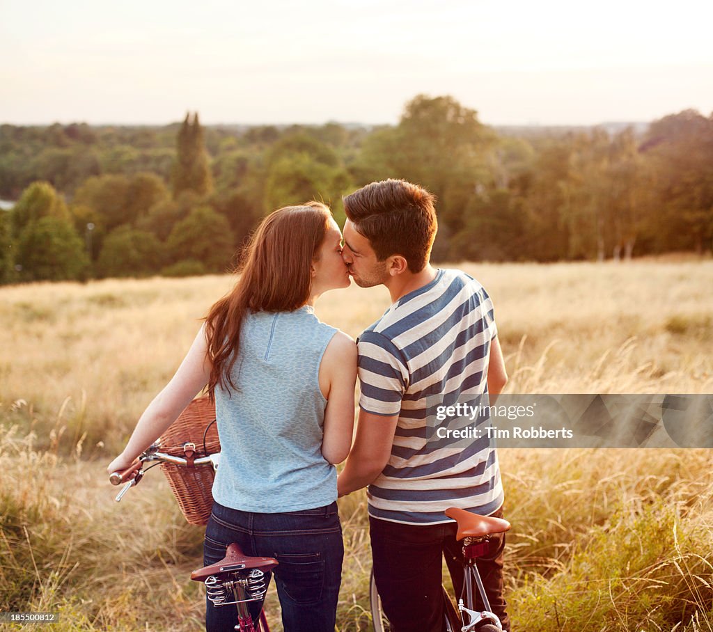 Couple kissing on bikes with view.