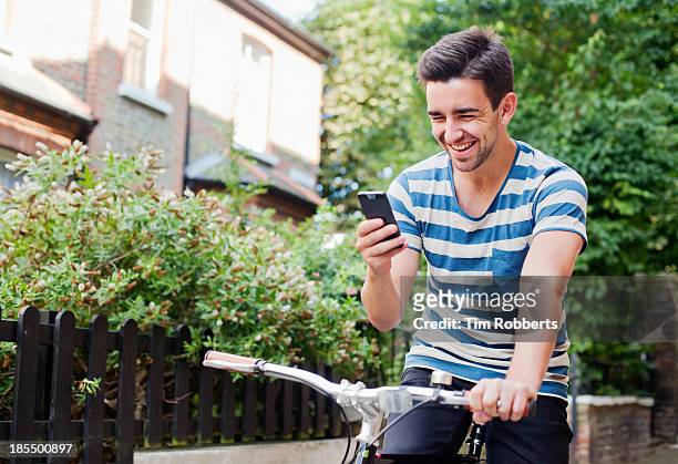 young man using smart phone on bike - tree smartphone stock pictures, royalty-free photos & images
