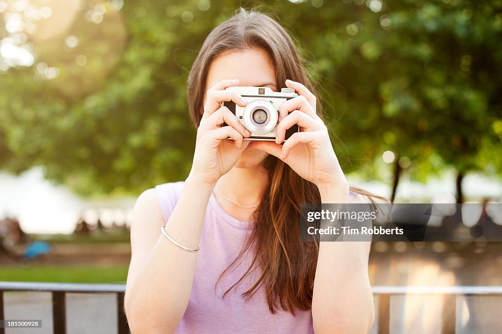 Young woman taking photo with retro camera.