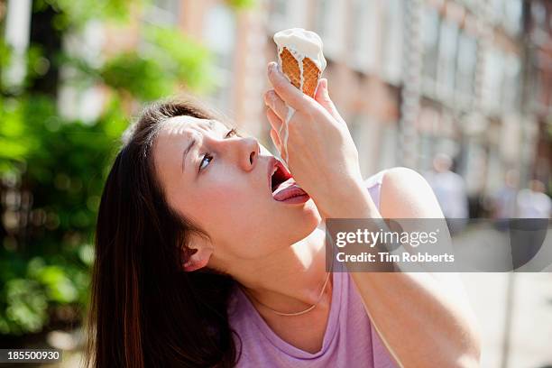 young woman licking melted ice cream from her hand - melting ice cream stock-fotos und bilder