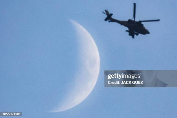 The waxing crescent moon is pictured as an Israeli air force attack helicopter flies over the northern Gaza Strip near the border with southern...