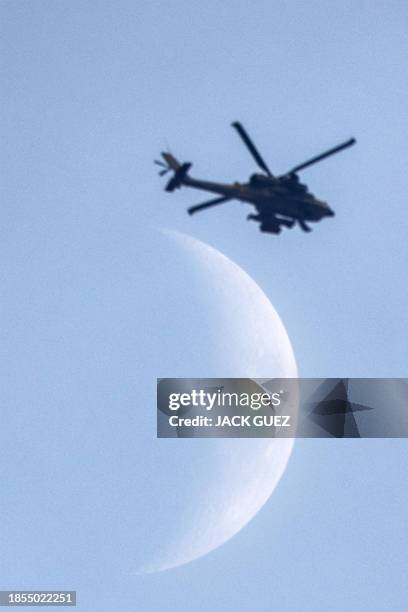 The waxing crescent moon is pictured as an Israeli air force attack helicopter flies over the northern Gaza Strip near the border with southern...