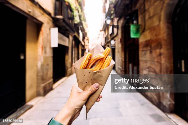 man eating churros on the streets of barcelona, personal perspective view, spain - sugar money stock pictures, royalty-free photos & images