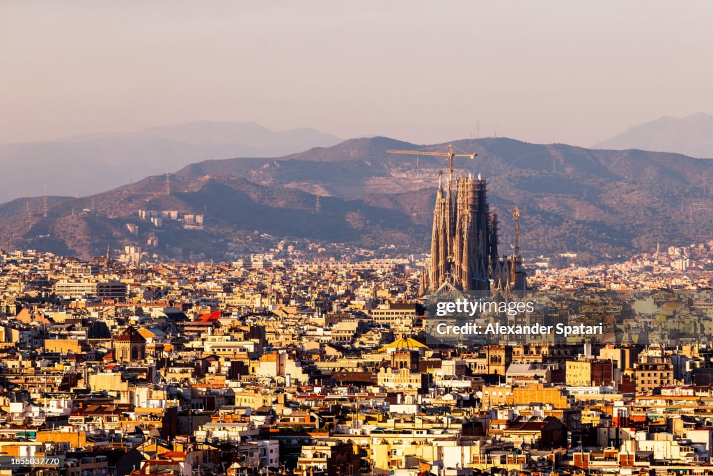 Barcelona cityscape with Sagrada Familia church and mountains in the background at sunset, Spain
