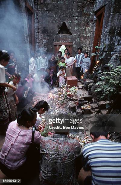 The Buddhist faithful on their knees worship in front of a statue of the Buddha inside the ruins of the Hindu Khmer temple of Wat Phu in Champassak...
